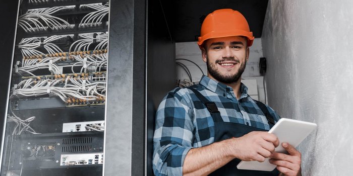 Ein Elektroniker der in einem Serviceraum ein Tablet bedient